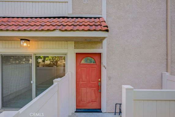 Front view of a house with a red door and a small tiled porch.