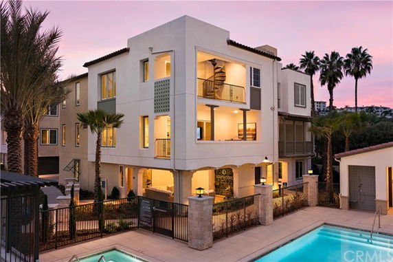 Front view of a multi-story modern building with a balcony and spiral staircase.