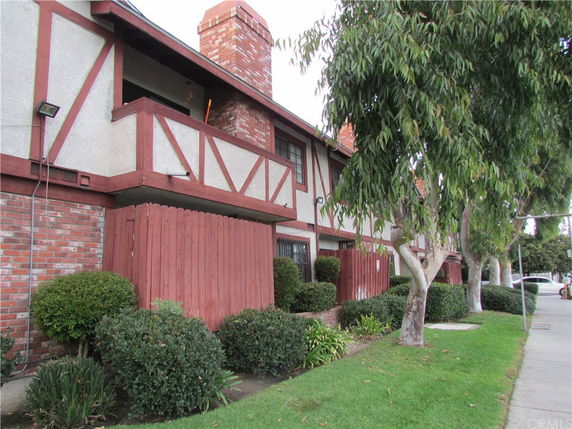 Front view of a two-story house with brick and wood paneling and a chimney.