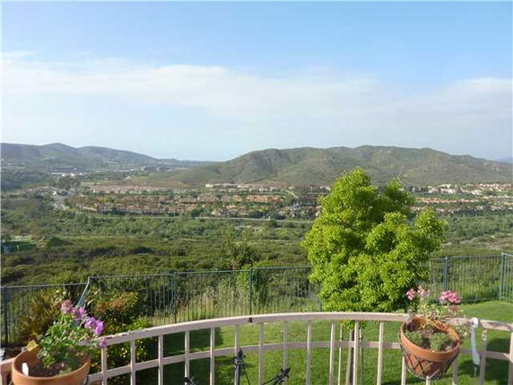 Panoramic view of hilly landscape with houses in the distance.