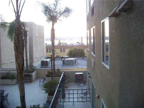 View from a building showing adjacent structures and a partial rooftop with palm trees.