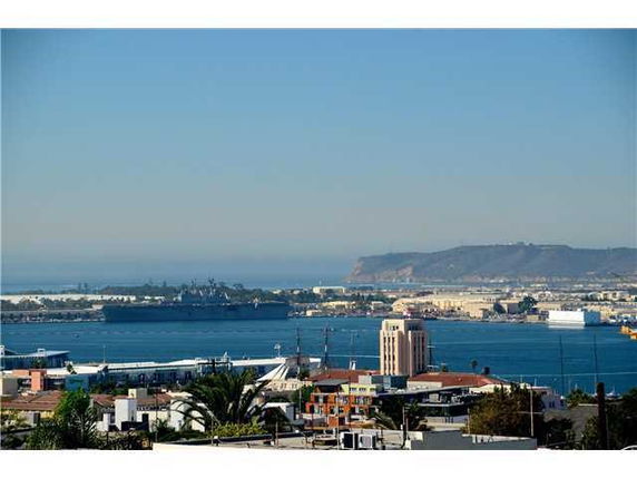 Panoramic view of the ocean and coastal cityscape with buildings and distant hills.