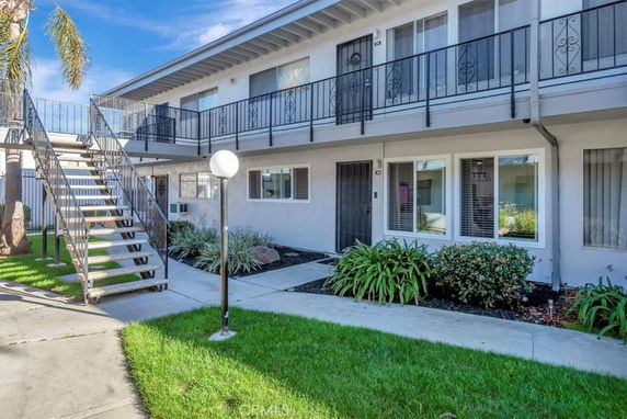 Front view of a two-story residential building with external stairs and balconies.