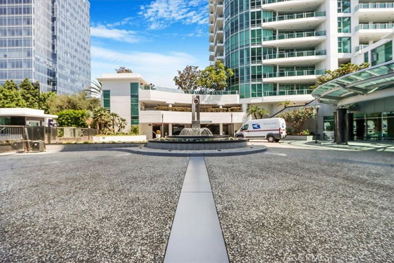 Front view of a multi-story modern building with a circular driveway and fountain.
