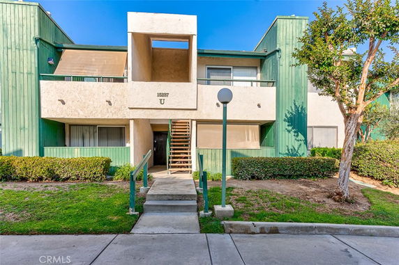 Front view of a multi-story building with green and beige exterior and outdoor stairs.