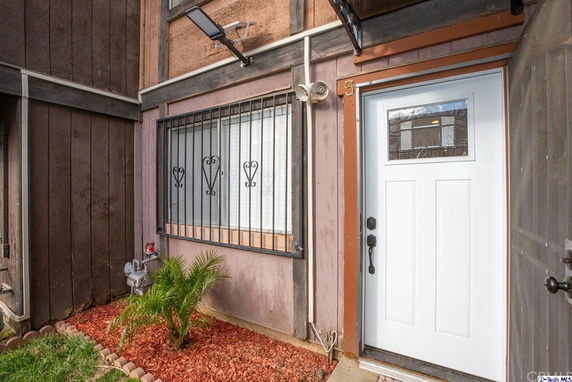 Front entrance of a building with a white door and barred window.