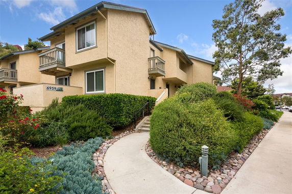 Front view of a multi-story house with balconies and landscaped pathway.
