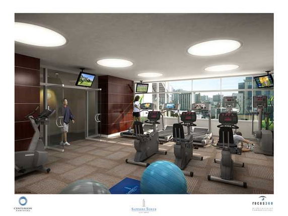 Interior view of a gym with exercise equipment and large windows.