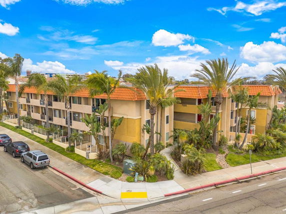 Front view of a multi-story apartment building with balconies and orange-tiled roof.