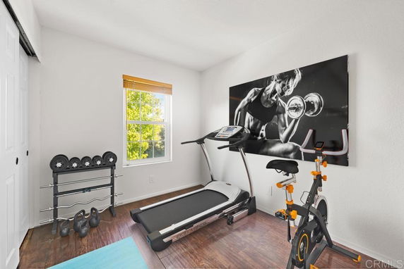 Home gym room with exercise equipment including a treadmill, exercise bike, and dumbbells.