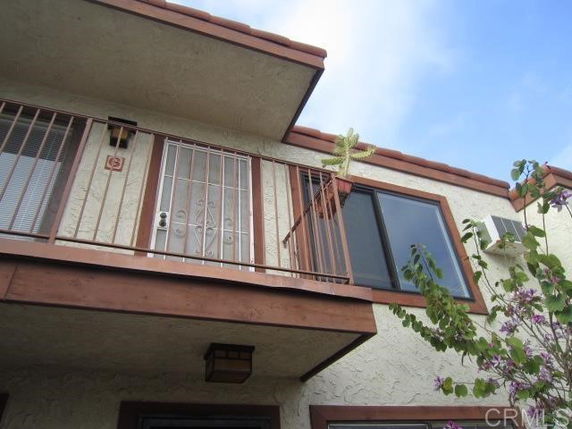 Front view of a two-story house with a small balcony and metal railing.