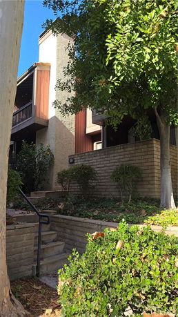 Front view of a multi-story building with a staircase and garden area.