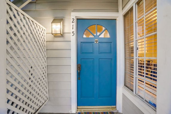 Front view of a house entrance with a blue door and window on the side.