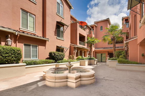 Front view of a multi-story terracotta-colored building with balconies and a central courtyard.