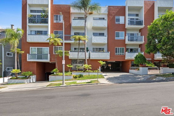 Front view of a multi-story building with balconies and a garage entrance.