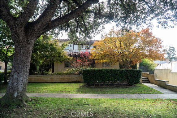 Front view of a two-story house partially obscured by trees and shrubs.
