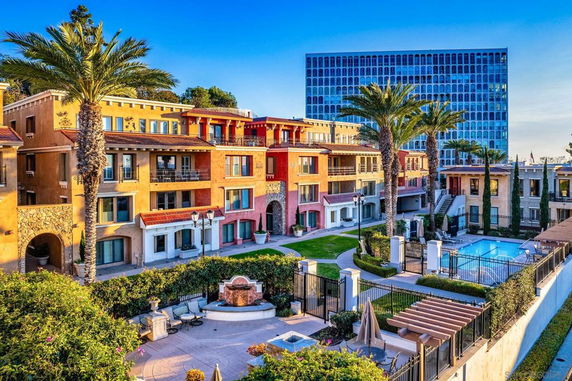 View of a multi-story residential complex with a swimming pool and landscaped courtyard.