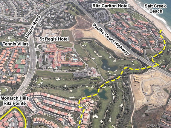 Aerial panoramic view of a coastal area featuring residential developments, hotels, and a highway.