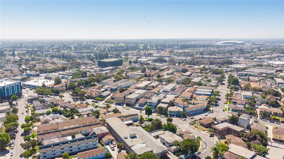 Wide aerial view of a suburban residential area with various buildings and distant landscape.