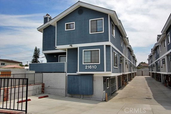 Front view of a multi-story blue apartment building with white trim.