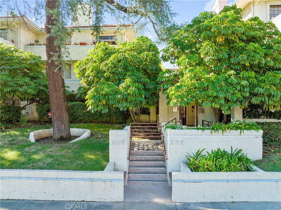 Front view of a multi-story residential building with a staircase leading to the entrance.