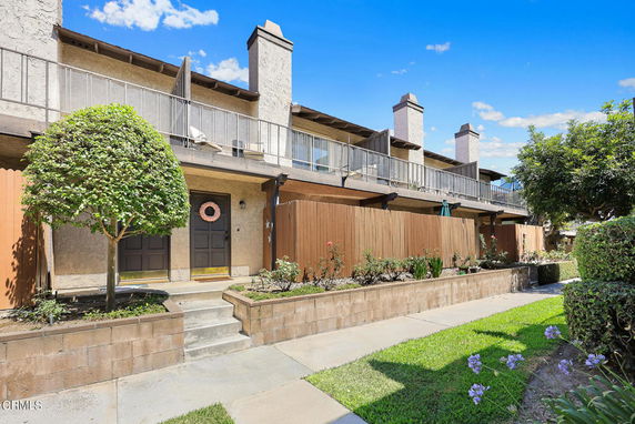 Front view of a two-story townhouse with a balcony and fenced front patio.