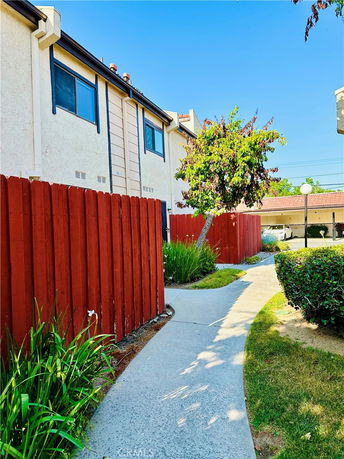Side view of a multi-story building with a red wooden fence and a pathway beside it.