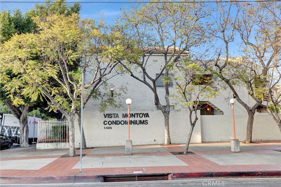Front view of a condominium building with trees on the sidewalk.