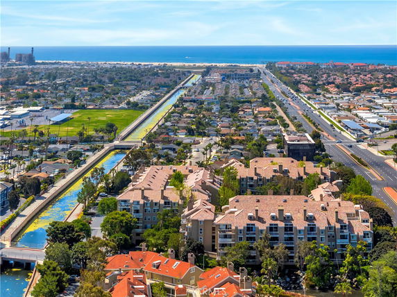 Panoramic view of a neighborhood with residential buildings, canal, and distant ocean.