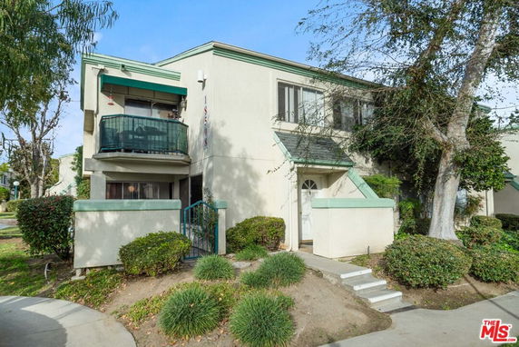 Front view of a two-story building with a small balcony and entrance steps.