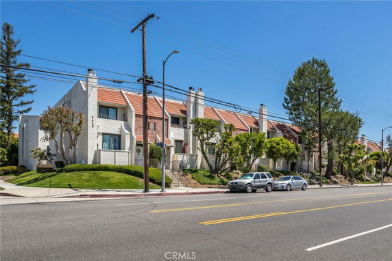 Front view of a multi-story residential building with orange roof tiles and white exterior walls.