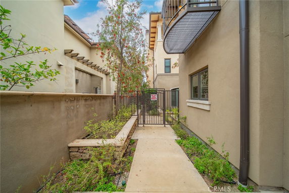 Exterior side view of a modern building with a gated entrance and greenery.