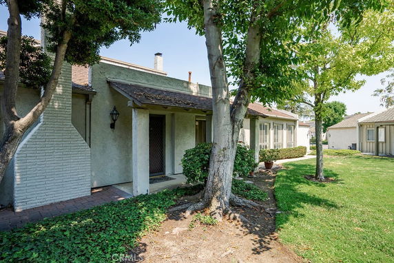 Front view of a single-story house with a chimney and a covered entryway.