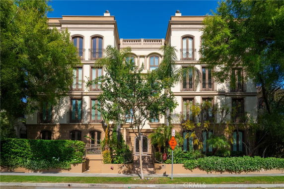 Front view of a multi-story residential building with trees and greenery.