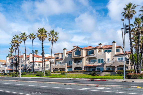Front view of a multi-story residential building with balconies and tiled roofs.