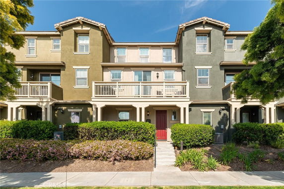Front view of a three-story residential building with multiple balconies and a pathway leading to the entrance.