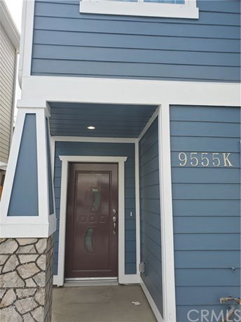 Front view of a blue house with a brown door and white trim.
