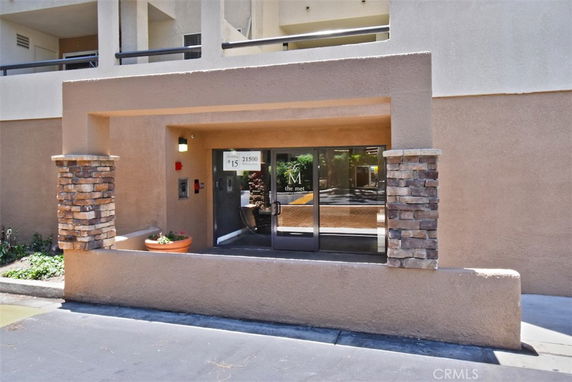 Front view of a building entrance with stone pillars and large glass doors.