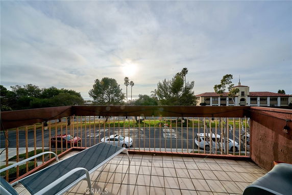 Balcony view overlooking a parking area and surrounding buildings.