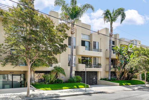 Front view of a multi-story residential building with balconies and gated entrance.