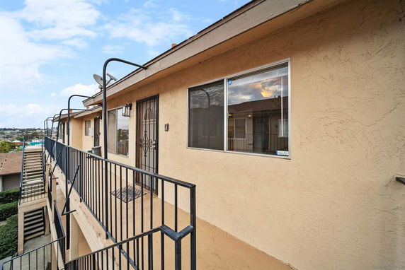 Exterior corridor of a multi-level apartment building with metal railings.