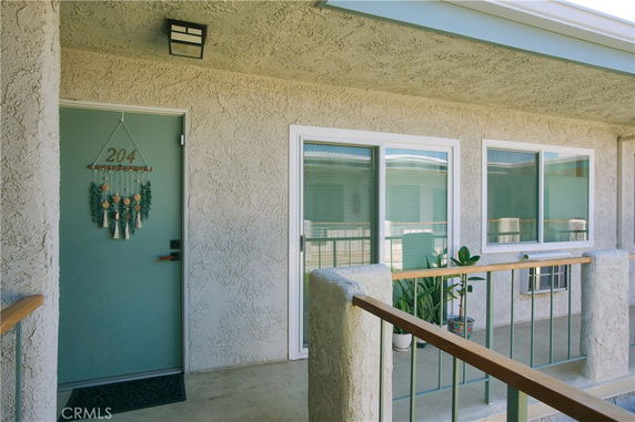 Exterior view of an apartment entrance with a green door and large windows.