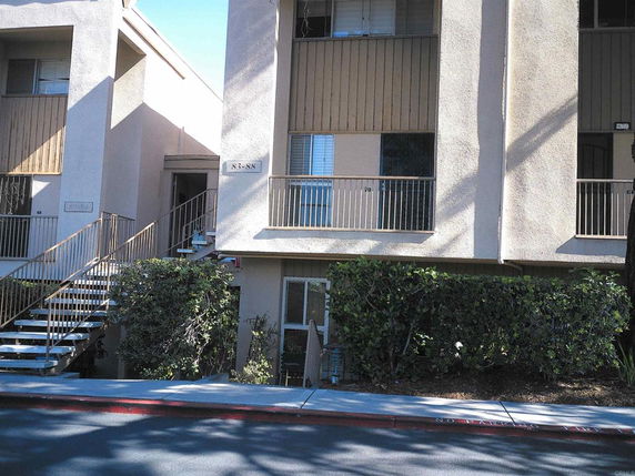 Front view of a multi-story apartment building with balconies and external staircases.