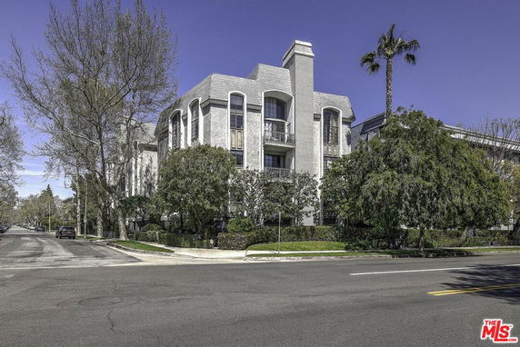 Front view of a multi-story building with a chimney and arched windows.
