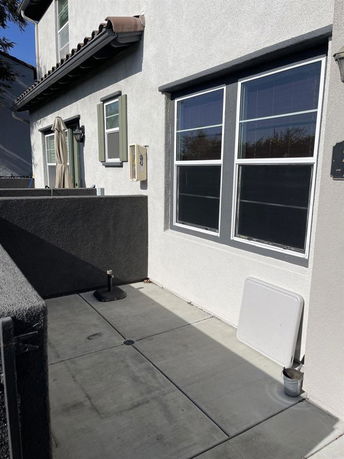 Side view of a two-story house with a concrete patio.