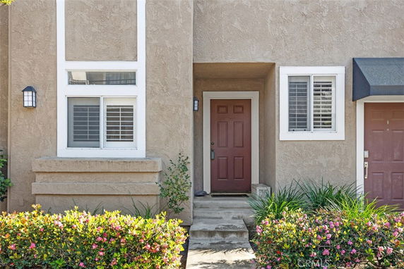 Front view of a house with a red door and white-framed windows.