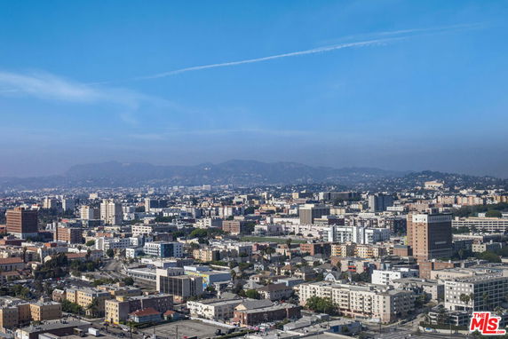 Wide-angle view of an urban cityscape with multiple buildings and distant hills.