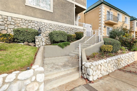 Front view of a multi-level building with stone exterior and stairway leading to an entrance.