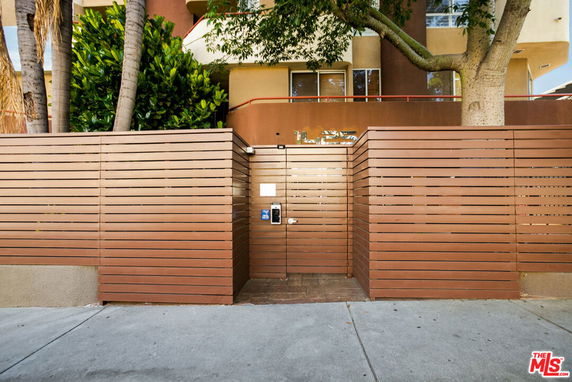 Front view of a multi-story building with wooden fence and entrance gate.