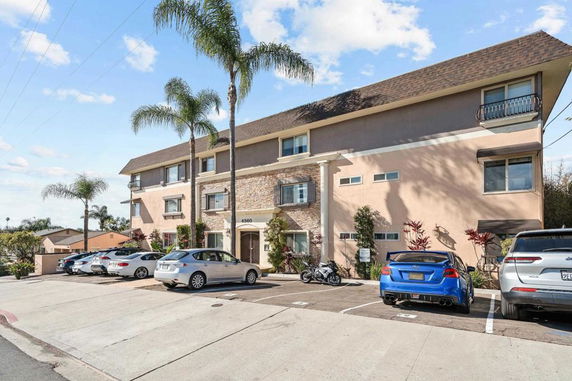 Front view of a multi-story residential building with parking spaces.